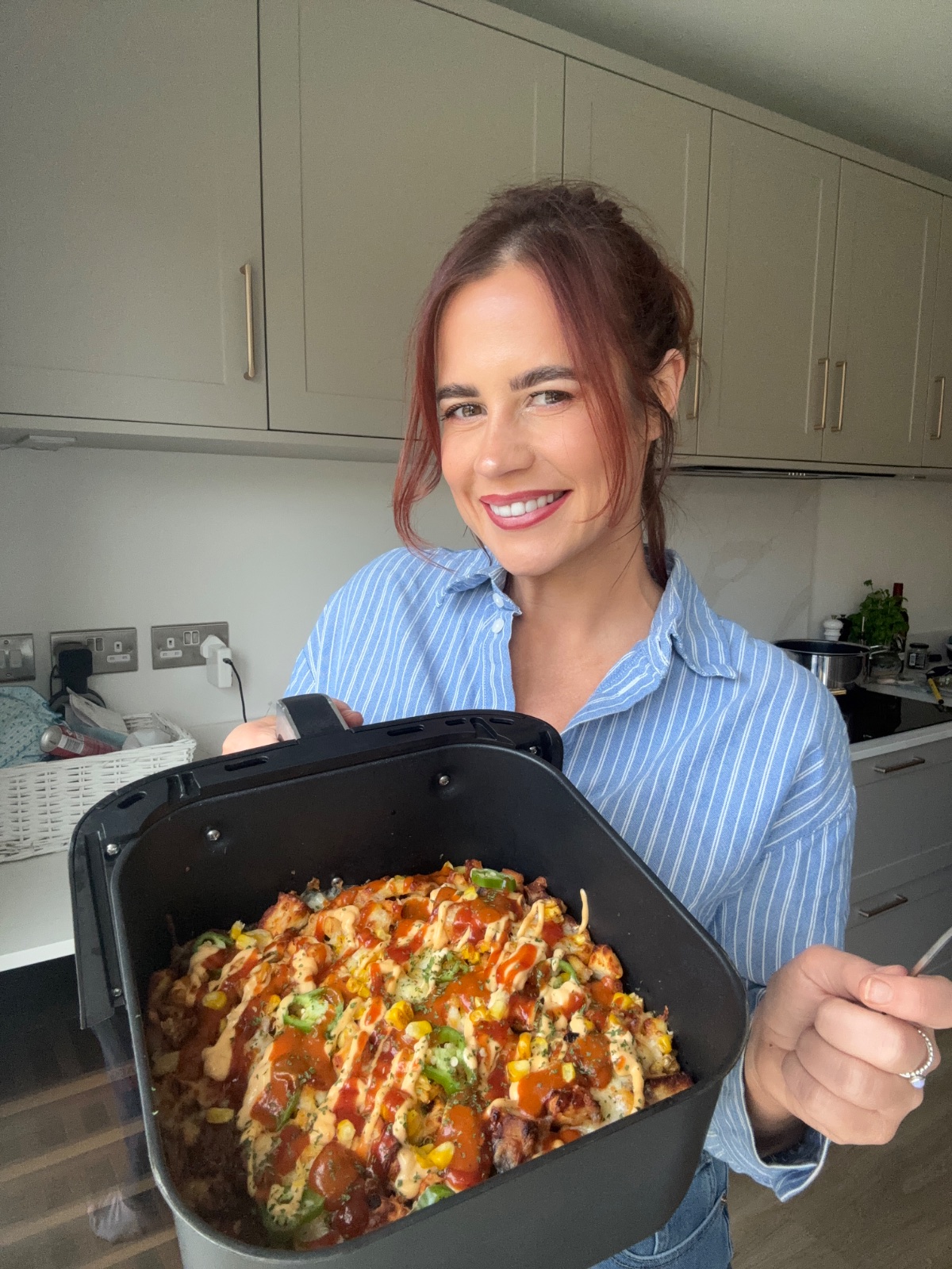 Hayley Dean in her kitchen holding a loaded air fryer basket